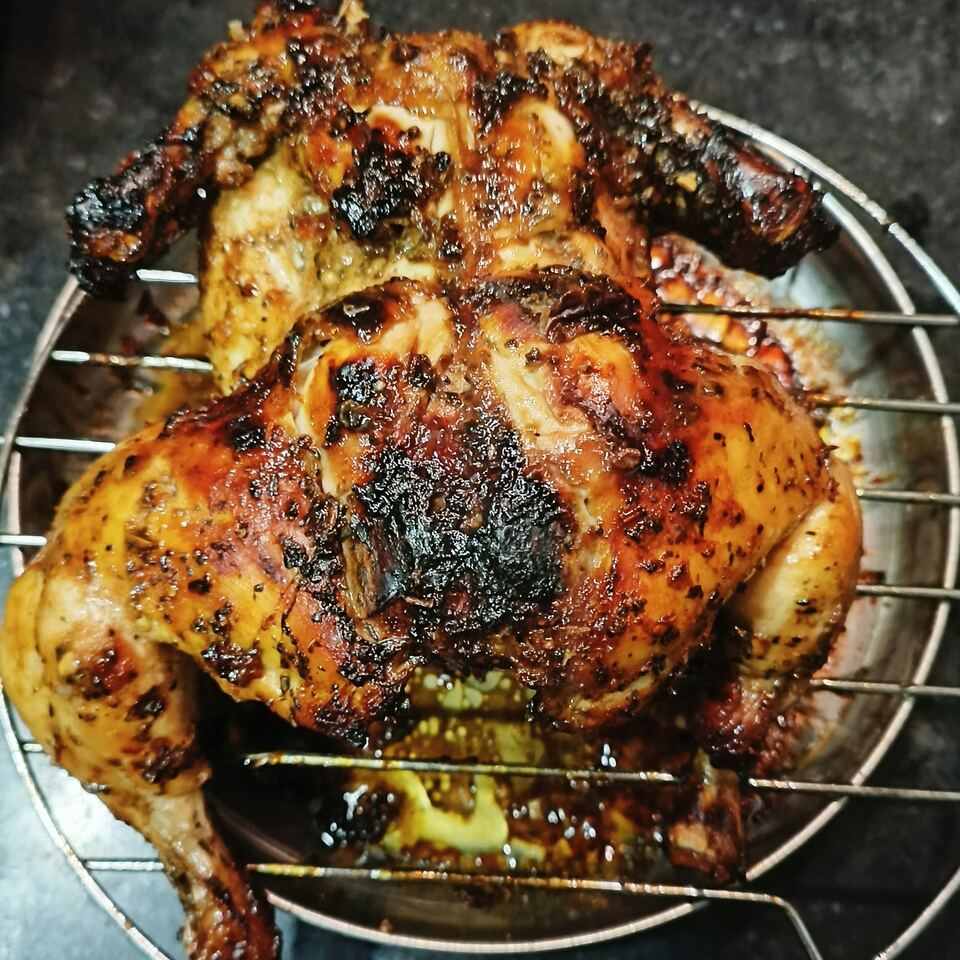 Frango inteiro no churrasco, bem tostado, sobre a grelha